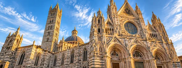 Siena Cathedral façade and bell tower under a blue sky
